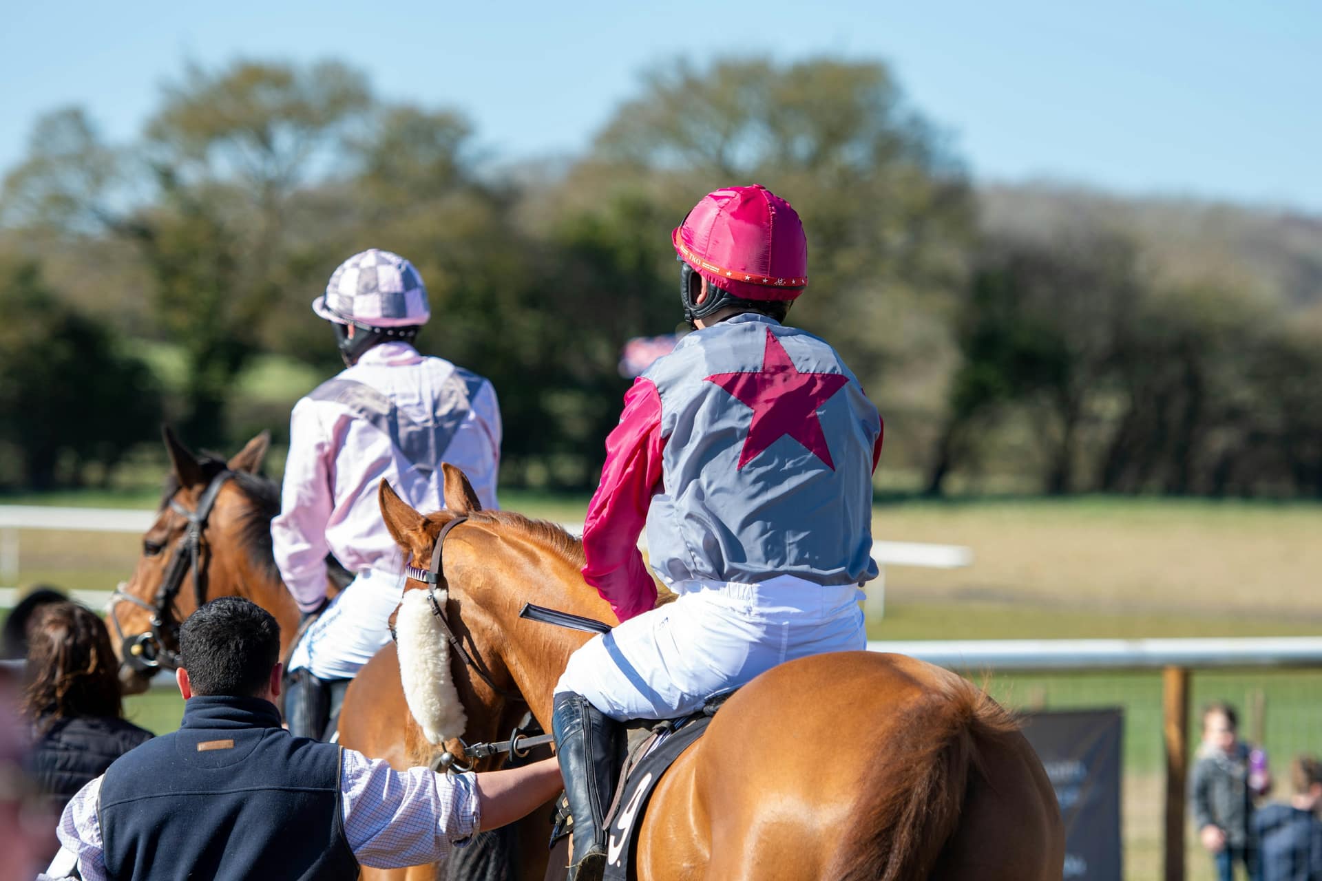 Jockeys in silks led out on their horses before a race, the moment to check what you learned reading the horse racing form